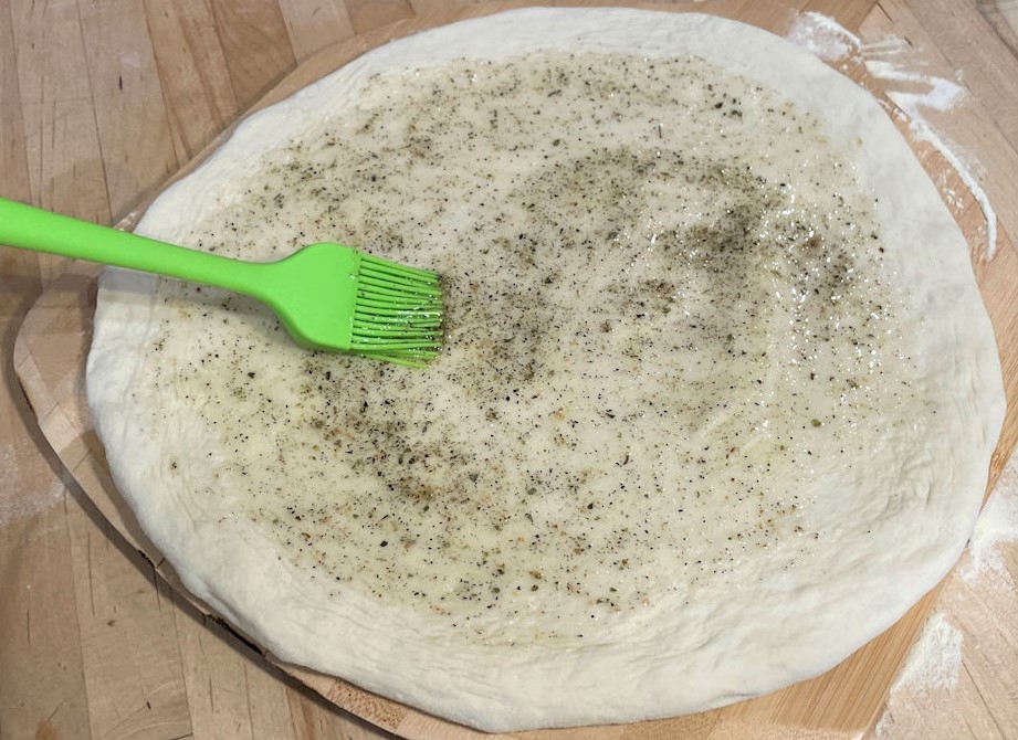 Spread the olive oil and seasoning on the crust using a brush