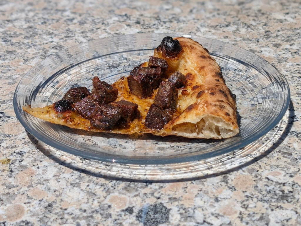 Slice of Spiedie pizza - just meat, sauce, and "bread".