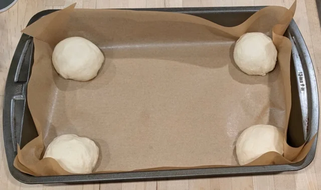 Hold the parchment paper down by first putting a roll in each corner.